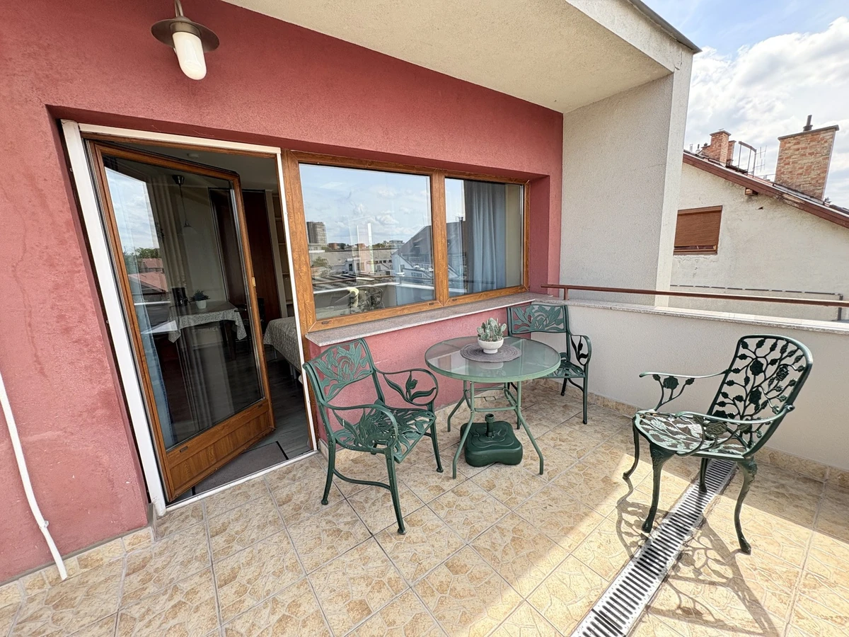 Az apartman piros falú terasza asztallal és székekkel